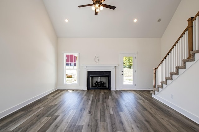 unfurnished living room featuring a high ceiling, ceiling fan, and dark wood-type flooring