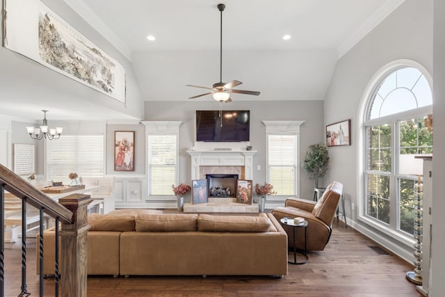 living room with a tile fireplace, wood-type flooring, ceiling fan with notable chandelier, and vaulted ceiling