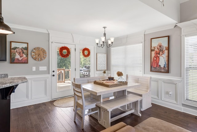 dining area with ornamental molding, dark hardwood / wood-style flooring, an inviting chandelier, and a healthy amount of sunlight