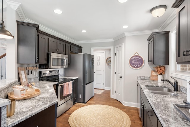 kitchen with pendant lighting, crown molding, sink, light wood-type flooring, and stainless steel appliances