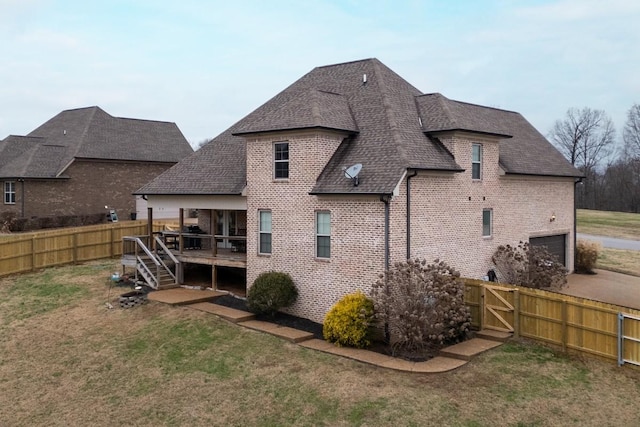 back of property featuring a yard, a garage, and a wooden deck