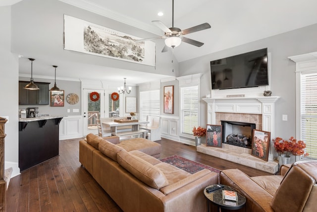 living room with ceiling fan with notable chandelier, dark hardwood / wood-style flooring, a tile fireplace, and vaulted ceiling