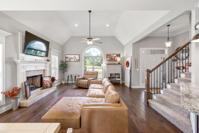 living room featuring ceiling fan, vaulted ceiling, dark hardwood / wood-style flooring, and a tiled fireplace