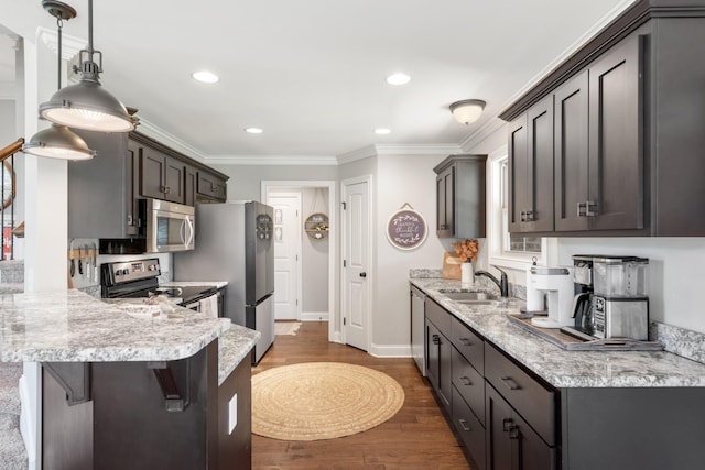 kitchen featuring a kitchen bar, ornamental molding, stainless steel appliances, sink, and pendant lighting