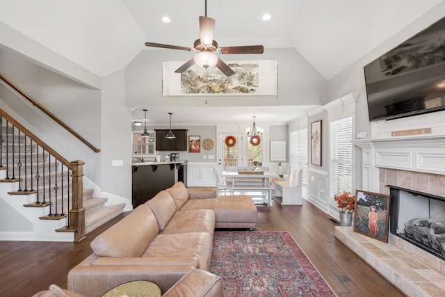 living room featuring a tile fireplace, lofted ceiling, dark hardwood / wood-style floors, and ceiling fan with notable chandelier