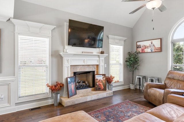 living room featuring a tile fireplace, dark hardwood / wood-style floors, ceiling fan, and lofted ceiling