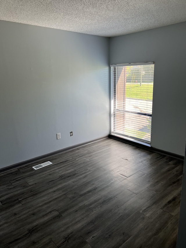 spare room featuring dark wood-type flooring and a textured ceiling