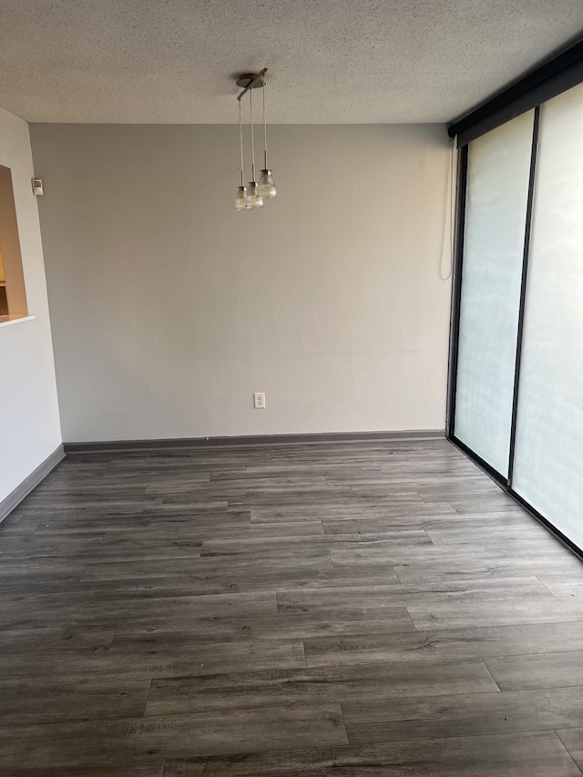 empty room with a wealth of natural light, dark hardwood / wood-style flooring, expansive windows, and a textured ceiling