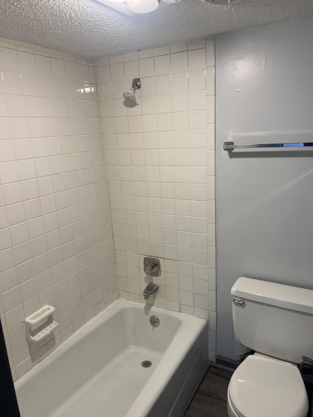 bathroom featuring hardwood / wood-style flooring, toilet, tiled shower / bath, and a textured ceiling