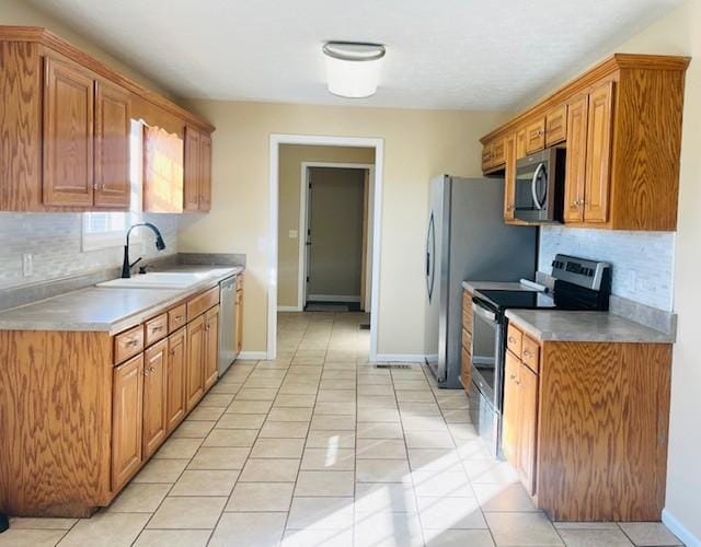 kitchen featuring appliances with stainless steel finishes, tasteful backsplash, light tile patterned floors, and sink