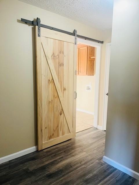 hall featuring a textured ceiling, a barn door, and dark wood-type flooring