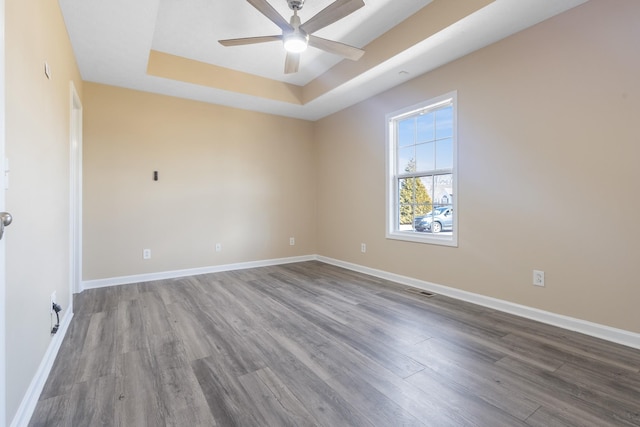 unfurnished room with hardwood / wood-style flooring, ceiling fan, and a tray ceiling