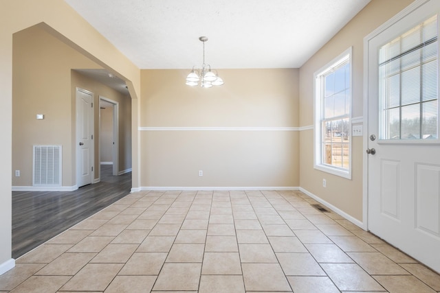 unfurnished dining area with a notable chandelier and light tile patterned floors
