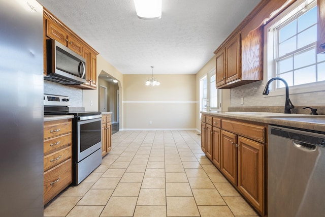 kitchen with light tile patterned flooring, pendant lighting, sink, decorative backsplash, and stainless steel appliances
