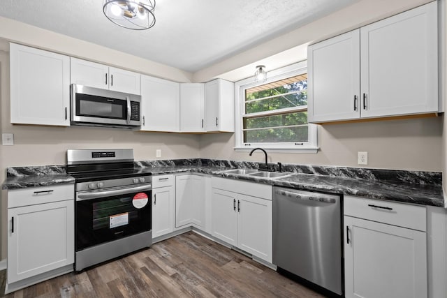 kitchen with sink, stainless steel appliances, dark hardwood / wood-style floors, dark stone countertops, and white cabinets