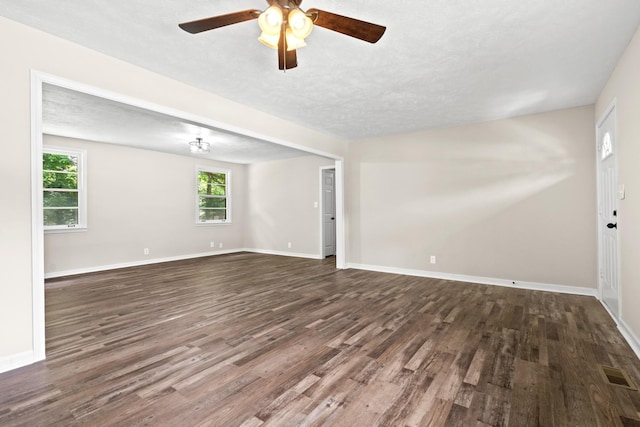 unfurnished room with ceiling fan, dark hardwood / wood-style flooring, a healthy amount of sunlight, and a textured ceiling