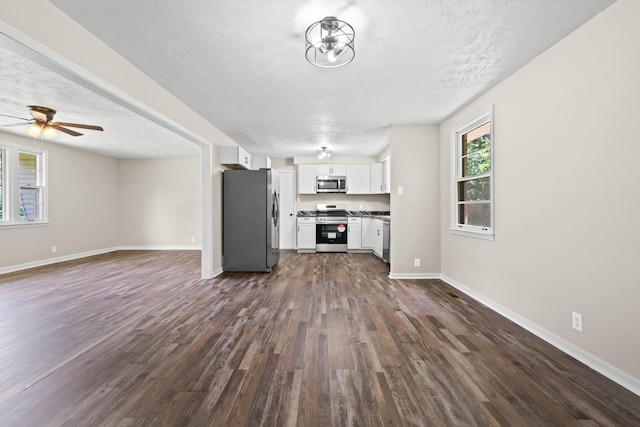 unfurnished living room featuring a textured ceiling, ceiling fan, and dark wood-type flooring