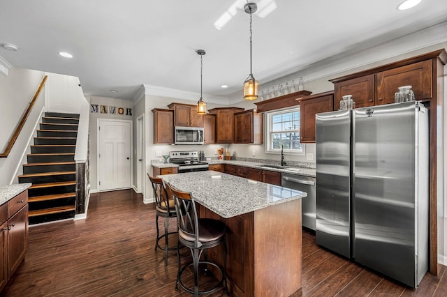 kitchen featuring light stone countertops, appliances with stainless steel finishes, decorative light fixtures, and a kitchen island