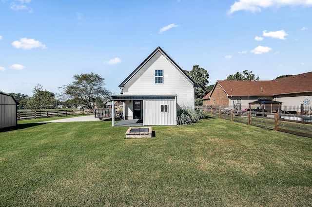 rear view of property with a lawn, a gazebo, and a shed