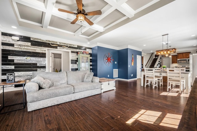 living room with dark wood-type flooring, coffered ceiling, crown molding, ceiling fan, and beam ceiling