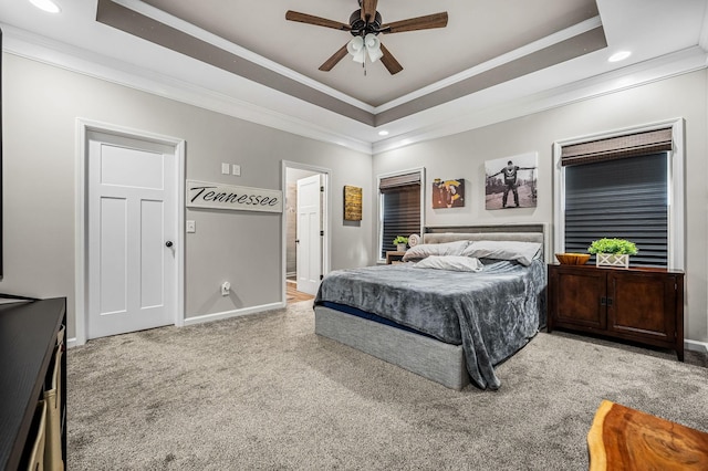 carpeted bedroom featuring a tray ceiling, connected bathroom, and ceiling fan