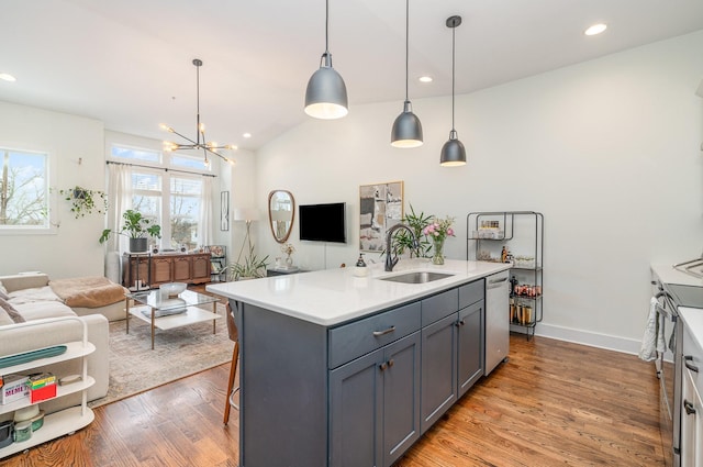 kitchen with stainless steel dishwasher, sink, decorative light fixtures, a center island with sink, and gray cabinets