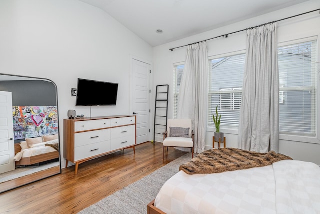 bedroom with light wood-type flooring and vaulted ceiling