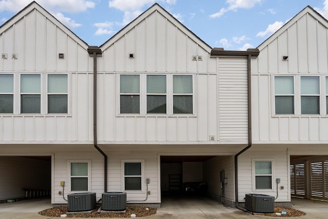 rear view of property featuring central AC unit and a carport