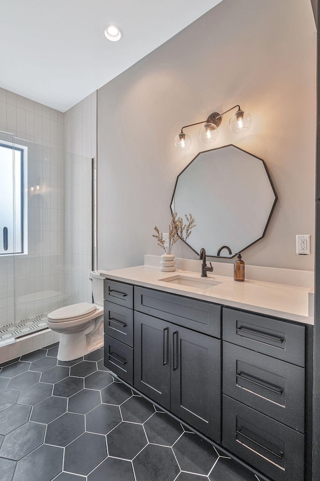 bathroom with tiled shower, vanity, and toilet