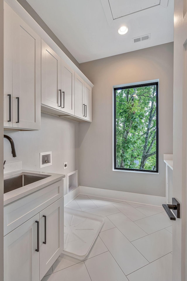 washroom with hookup for an electric dryer, washer hookup, cabinets, sink, and light tile patterned floors