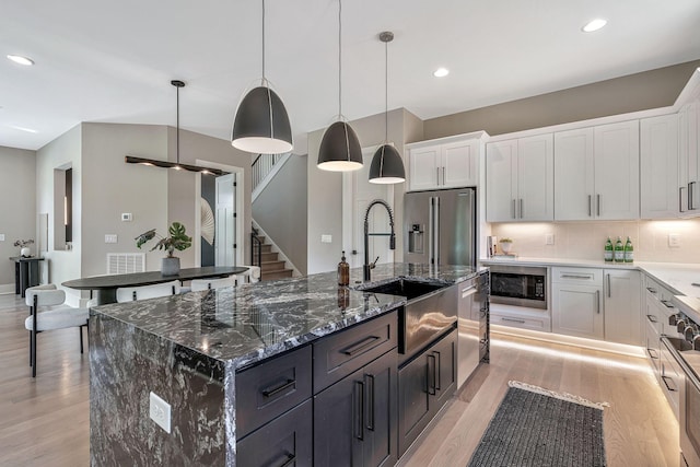 kitchen featuring appliances with stainless steel finishes, white cabinetry, and an island with sink