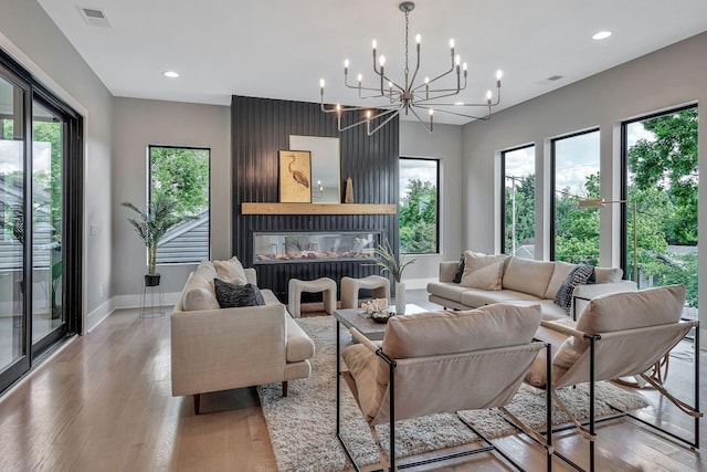 living room featuring a multi sided fireplace, a chandelier, and light wood-type flooring