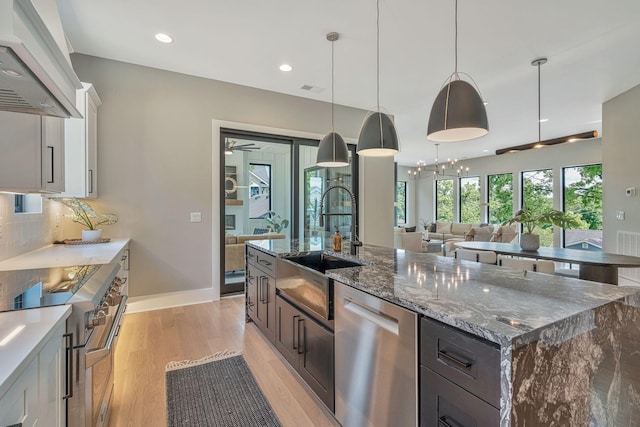 kitchen featuring white cabinets, custom exhaust hood, stainless steel appliances, and dark stone counters