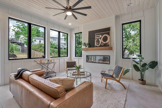 interior space with ceiling fan, a large fireplace, and wooden ceiling