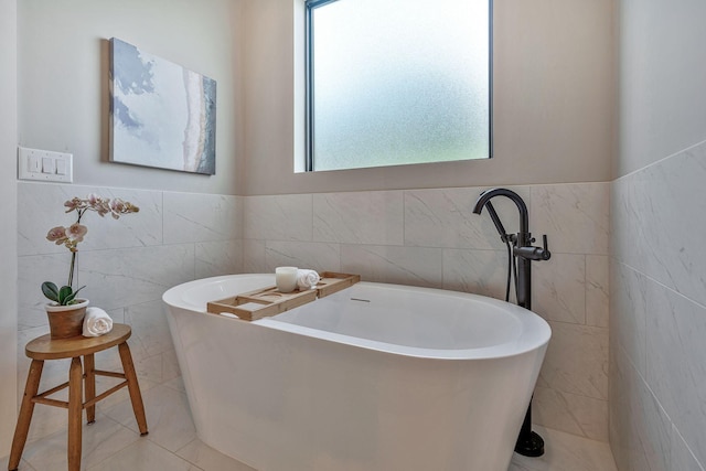 bathroom featuring a washtub, tile walls, and a wealth of natural light