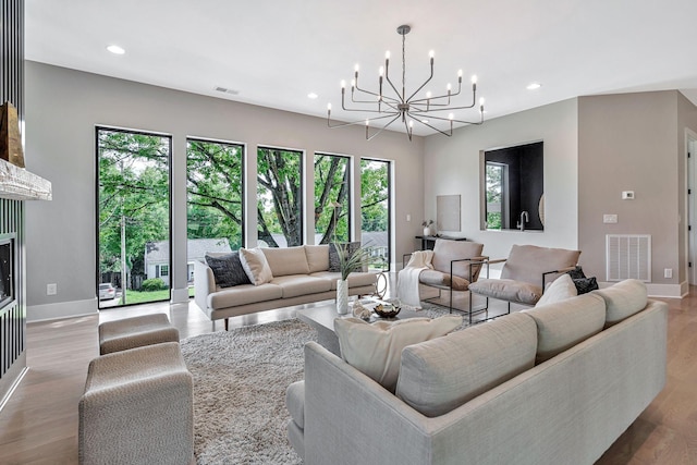 living room featuring a fireplace, light hardwood / wood-style flooring, and a chandelier