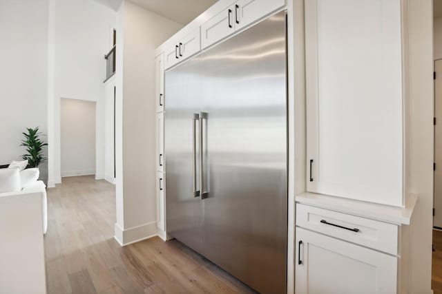 kitchen with light hardwood / wood-style floors, white cabinetry, and built in refrigerator