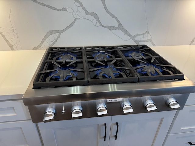 room details featuring white cabinets and stainless steel gas stovetop