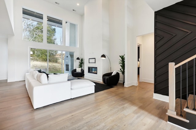 living room with a fireplace, a high ceiling, and light wood-type flooring