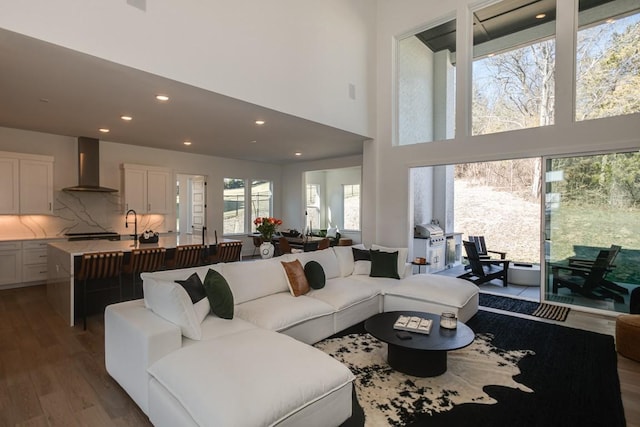 living room with hardwood / wood-style flooring, sink, and a high ceiling