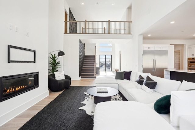 living room with a towering ceiling and light wood-type flooring