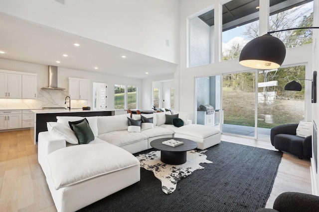 living room with light hardwood / wood-style floors and a towering ceiling