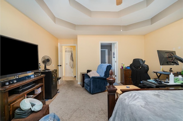 carpeted bedroom featuring a raised ceiling and ceiling fan