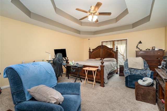 carpeted bedroom featuring a tray ceiling and ceiling fan