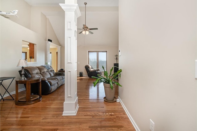 living room featuring ornate columns, ceiling fan, a towering ceiling, and hardwood / wood-style flooring