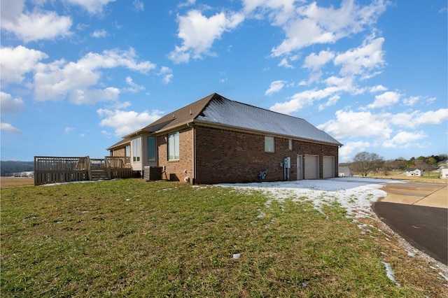 view of side of home featuring a wooden deck, a yard, cooling unit, and a garage