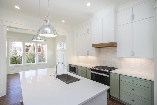 kitchen featuring sink, appliances with stainless steel finishes, a kitchen island with sink, white cabinets, and decorative light fixtures