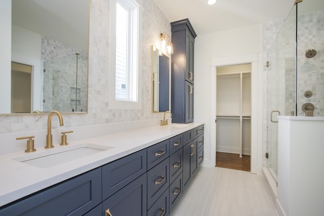 bathroom featuring vanity, tile patterned flooring, a shower with door, and backsplash