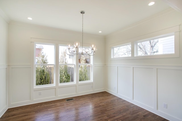 unfurnished dining area with a notable chandelier, dark wood-type flooring, plenty of natural light, and ornamental molding