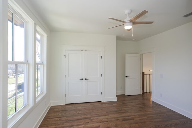 unfurnished bedroom featuring dark wood-type flooring, ceiling fan, and a closet